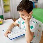 education, childhood and technology concept – happy student boy