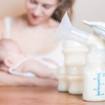 Manual breast pump and mother feeding a newborn baby